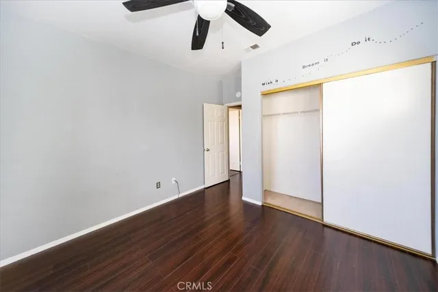 an empty room with wooden floor ceiling fan and windows