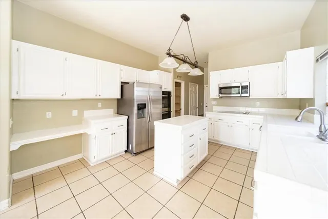 a kitchen with stainless steel appliances kitchen island granite countertop a sink a stove a refrigerator and cabinets