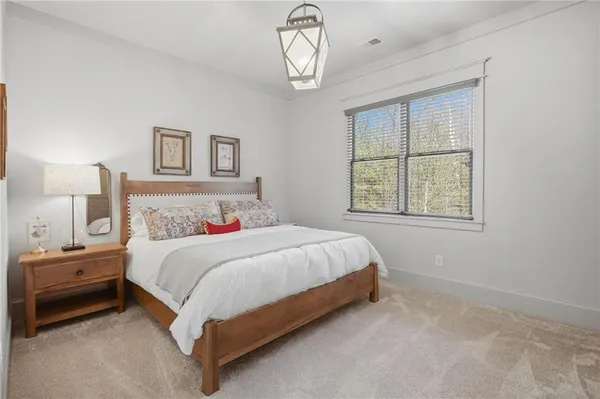 a bedroom with a bed and a lamp on a dresser
