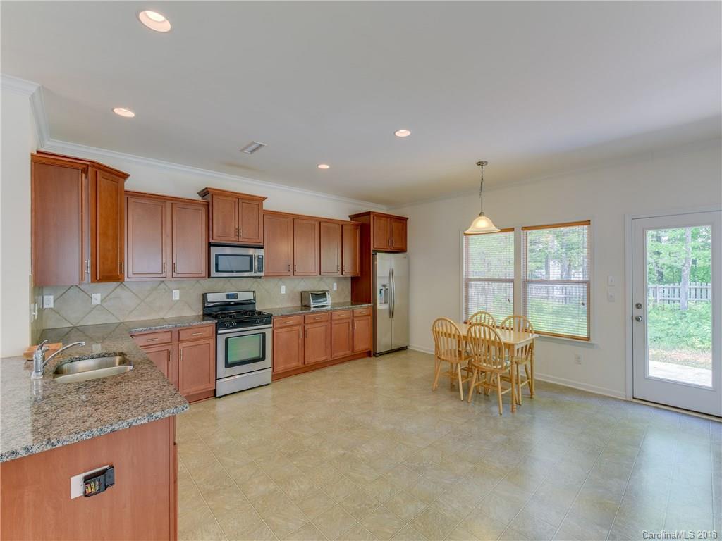 9502 Fernspray Road Charlotte, NC 28215 - Photo 4 of 20 a open kitchen with stainless steel appliances granite countertop a stove top oven a sink a dining table and chairs with wooden floor