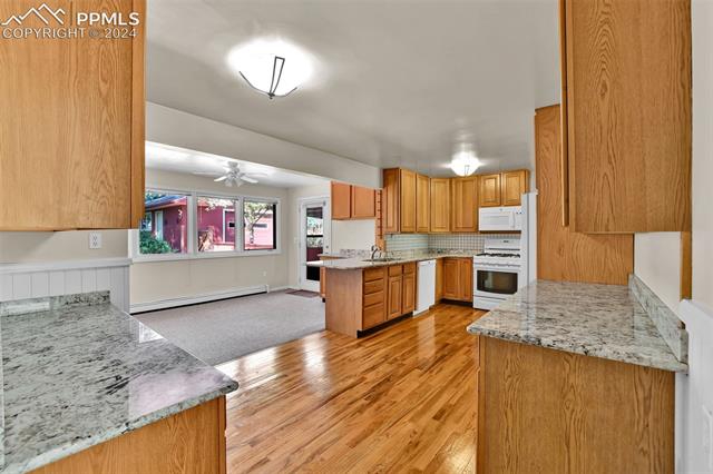 1404 West Cheyenne Road Colorado Springs, CO 80906 - Photo 24 of 50 Kitchen with sink, kitchen peninsula, white appliances, a baseboard heating unit, and light hardwood / wood-style floors