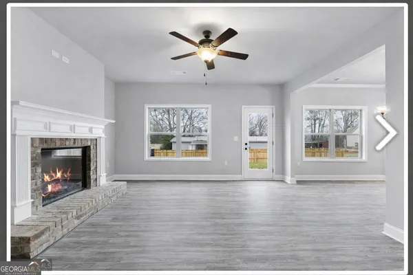 a view of an empty room with wooden floor and a fireplace