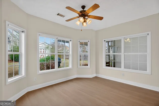 a view of an empty room with a window and wooden floor