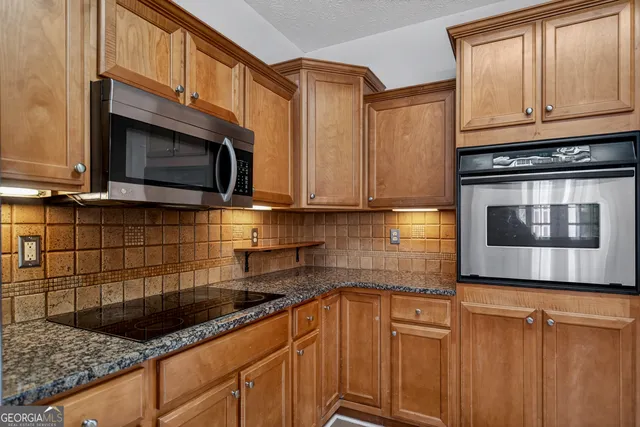 a kitchen with stainless steel appliances granite countertop a sink a stove microwave and cabinets