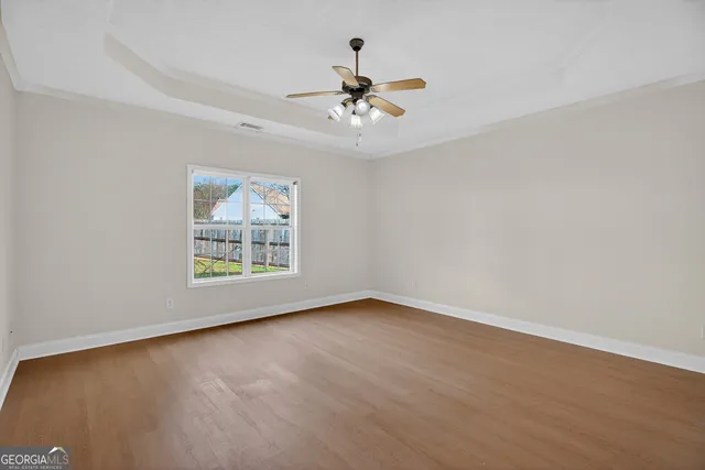 an empty room with ceiling fan and window