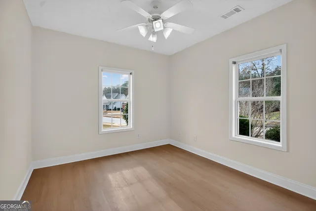 an empty room with a window and ceiling fan