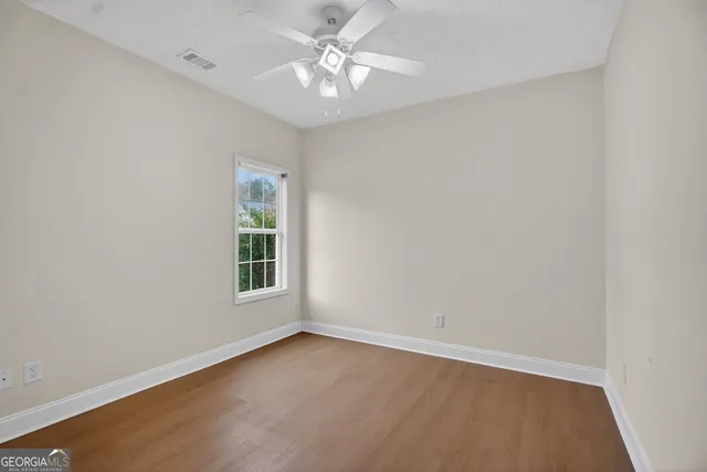 an empty room with a window and a fan