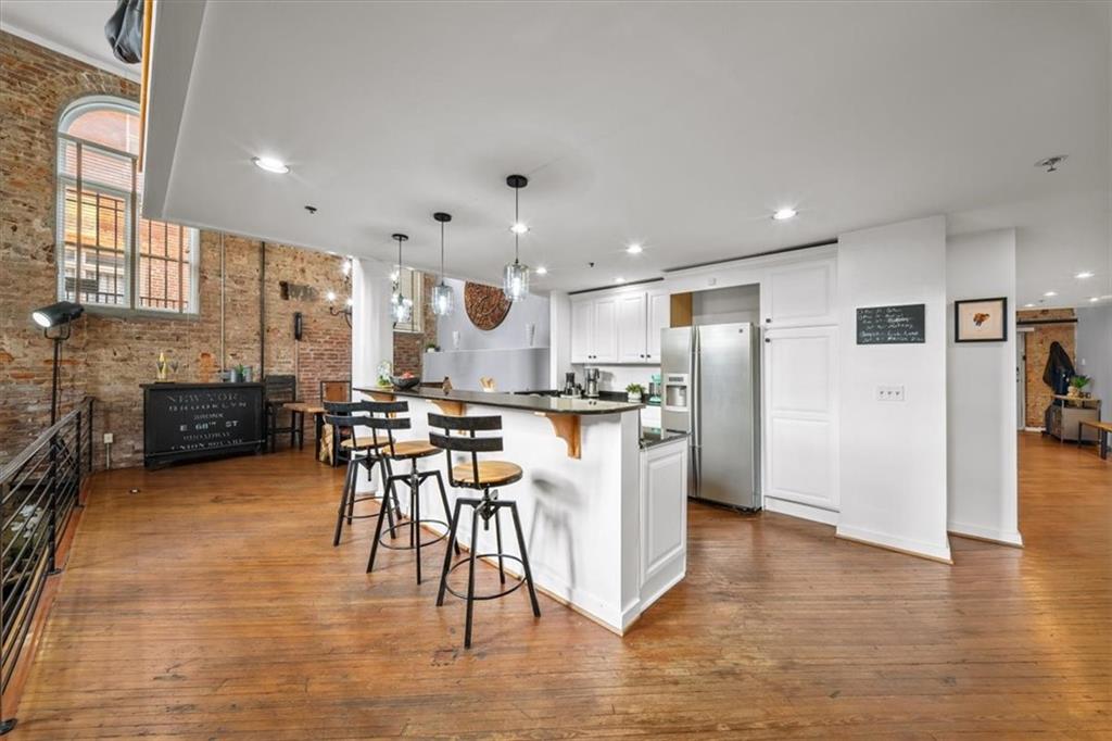 330 Peters Street Southwest, Unit 105 Atlanta, GA 30313 - Photo 5 of 27 a kitchen with stainless steel appliances kitchen island granite countertop a refrigerator a stove a sink a dining table and chairs with wooden floor