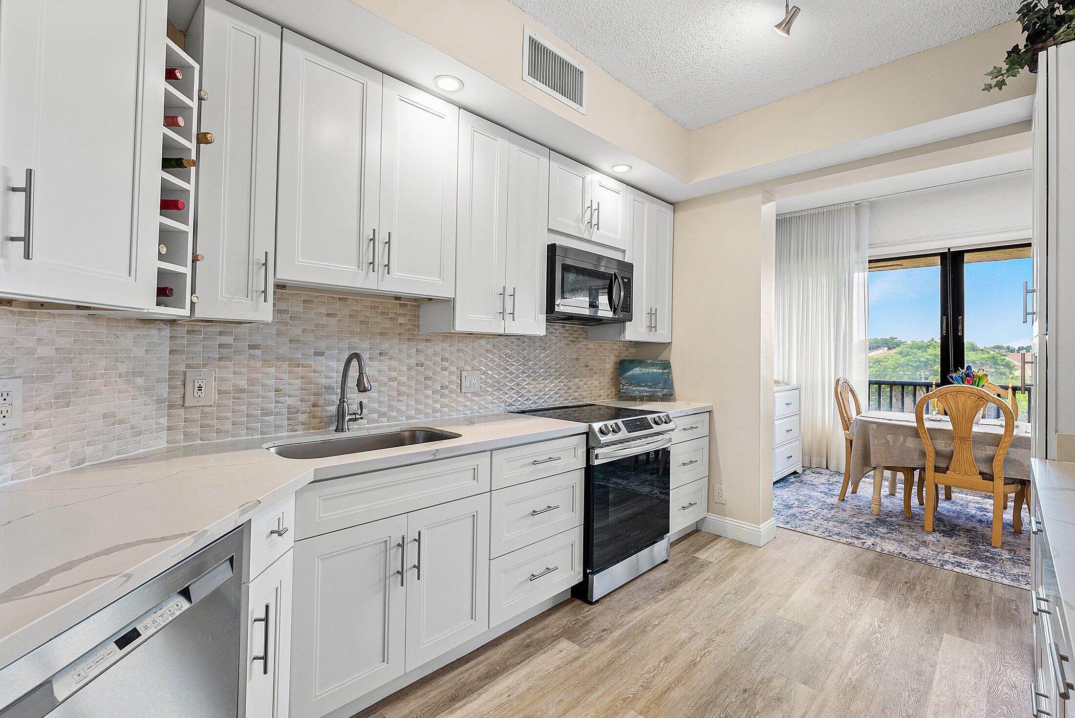 7546 La Paz Boulevard, Unit 404 Boca Raton, FL 33433 - Photo 17 of 47 a kitchen with stainless steel appliances granite countertop a sink stove and cabinets
