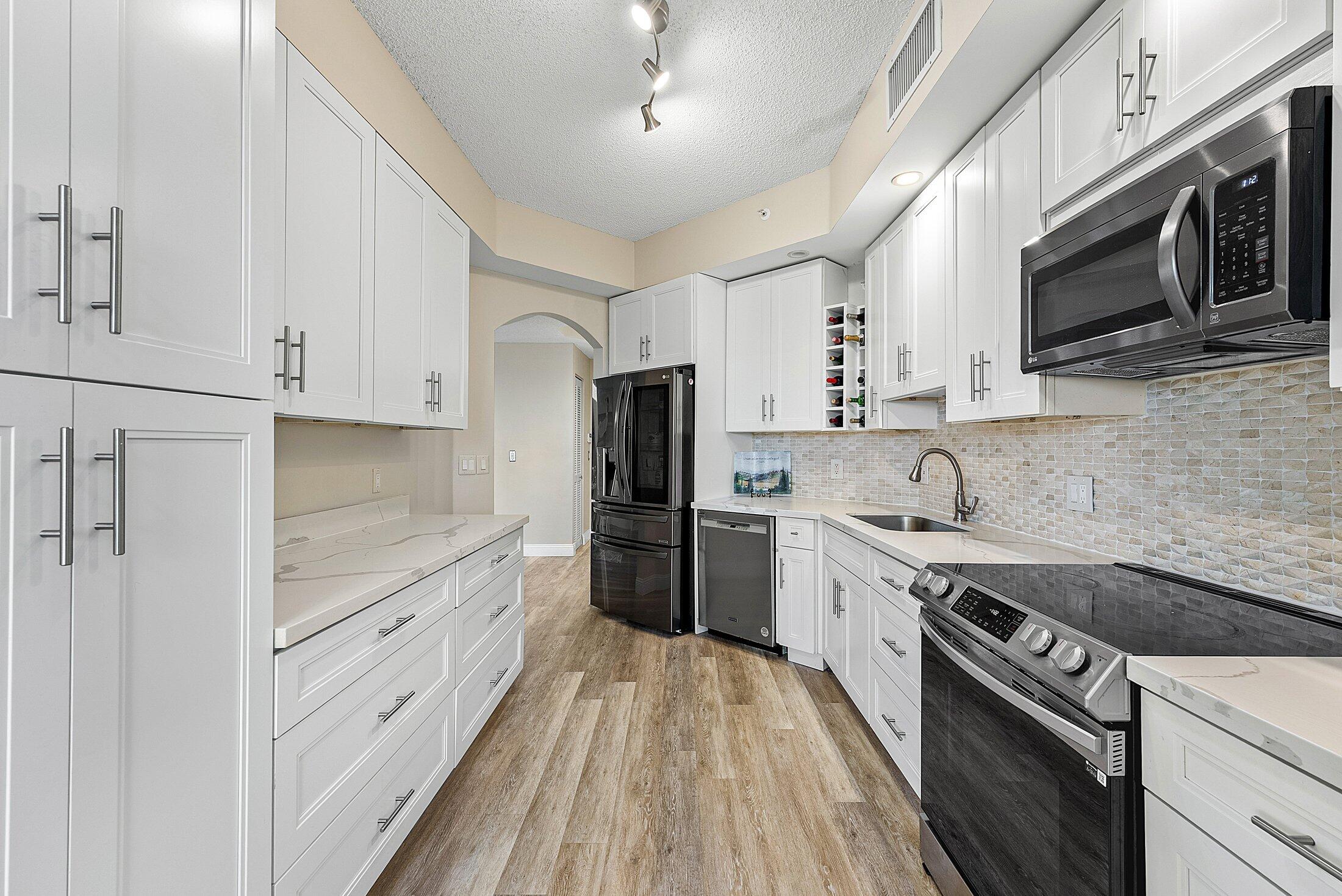 7546 La Paz Boulevard, Unit 404 Boca Raton, FL 33433 - Photo 18 of 47 a kitchen with stainless steel appliances a stove microwave and cabinets