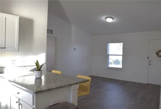a kitchen with granite countertop a sink cabinets and wooden floor
