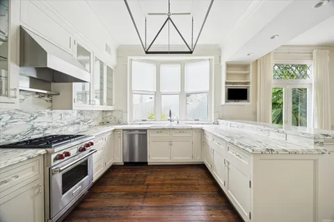 a kitchen with granite countertop stainless steel appliances a stove sink and refrigerator