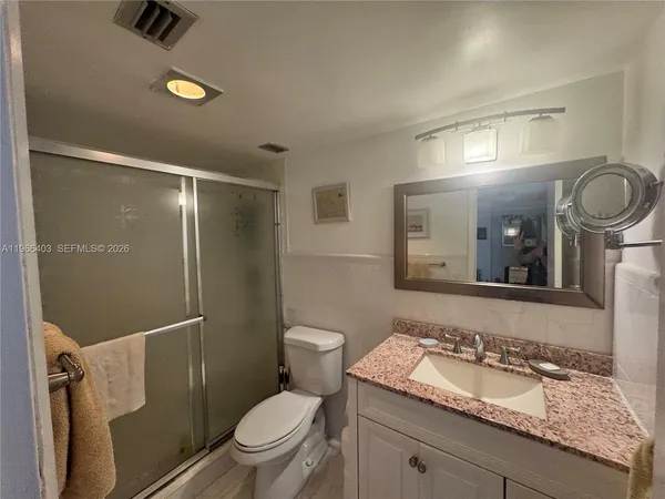 a bathroom with a granite countertop sink toilet a mirror and shower