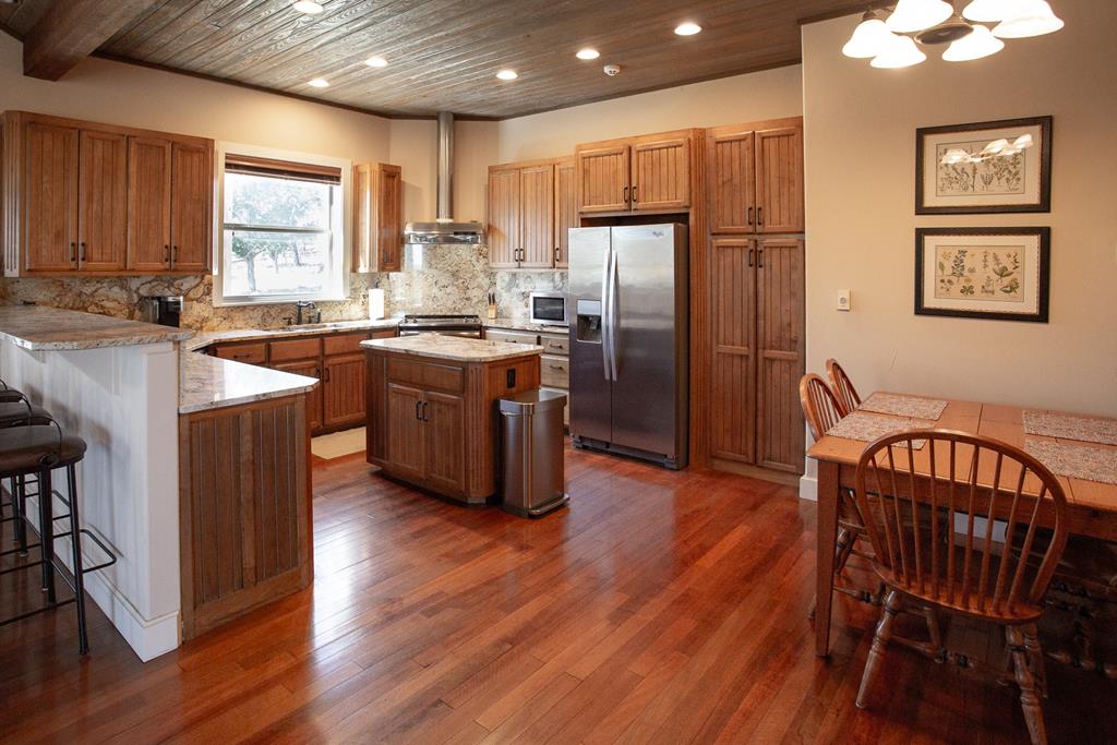 475 River Bend Road West Hunt, TX 78024 - Photo 17 of 87 a kitchen with stainless steel appliances granite countertop a refrigerator a stove a sink dishwasher and a dining table with wooden floor