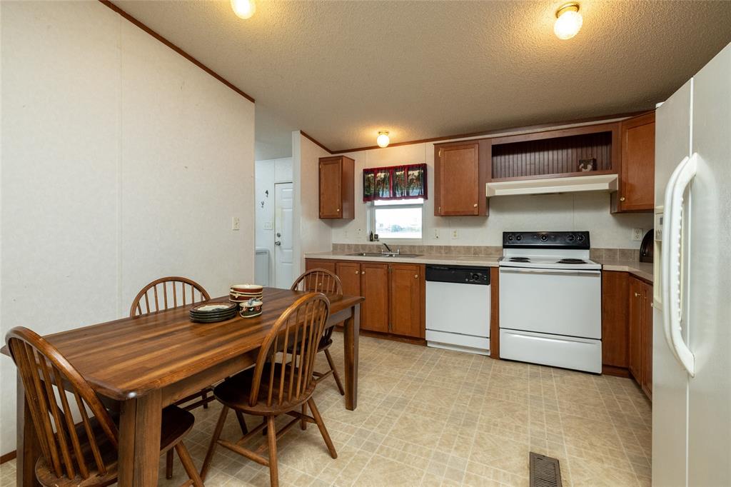 207 Lazy B Lane Springtown, TX 76082 - Photo 13 of 39 Kitchen with sink, a textured ceiling, light tile patterned flooring, and white appliances