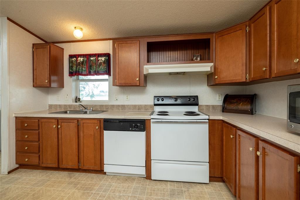 207 Lazy B Lane Springtown, TX 76082 - Photo 15 of 39 Kitchen featuring a textured ceiling, white appliances, wall chimney exhaust hood, and sink