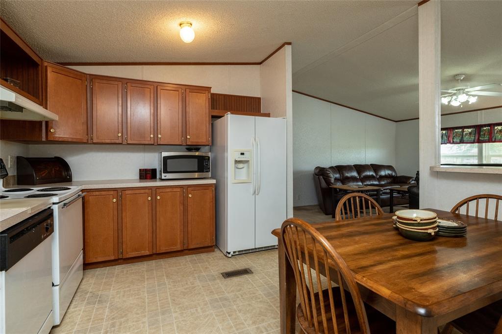 207 Lazy B Lane Springtown, TX 76082 - Photo 17 of 39 Kitchen with ceiling fan, ornamental molding, lofted ceiling, light tile patterned flooring, and white appliances