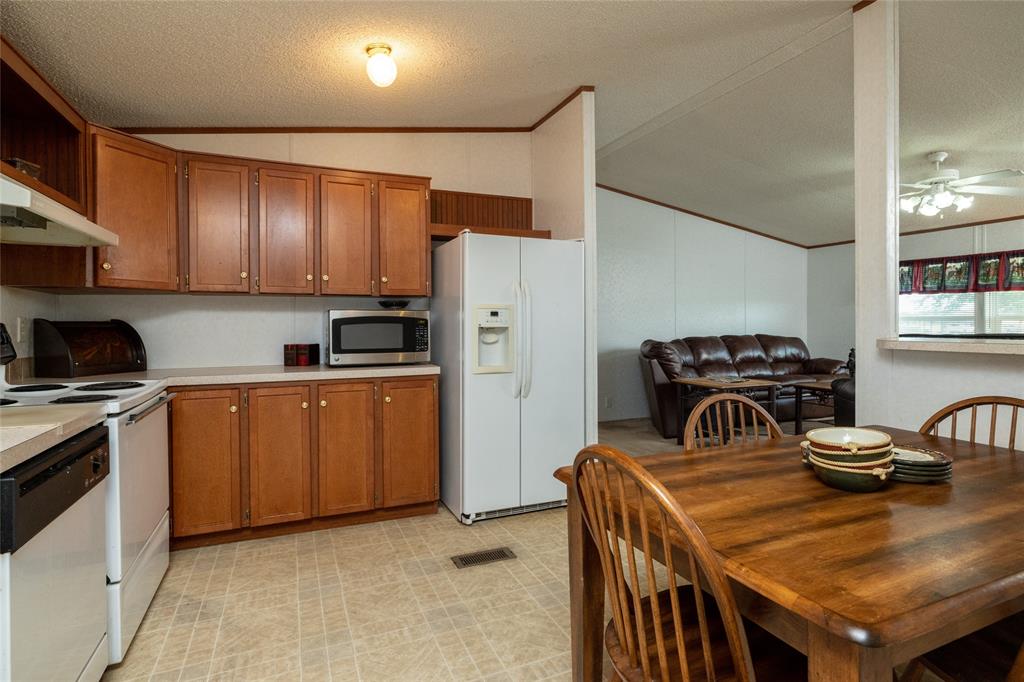 207 Lazy B Lane Springtown, TX 76082 - Photo 18 of 39 Kitchen featuring ceiling fan, vaulted ceiling, light tile patterned floors, a textured ceiling, and white appliances