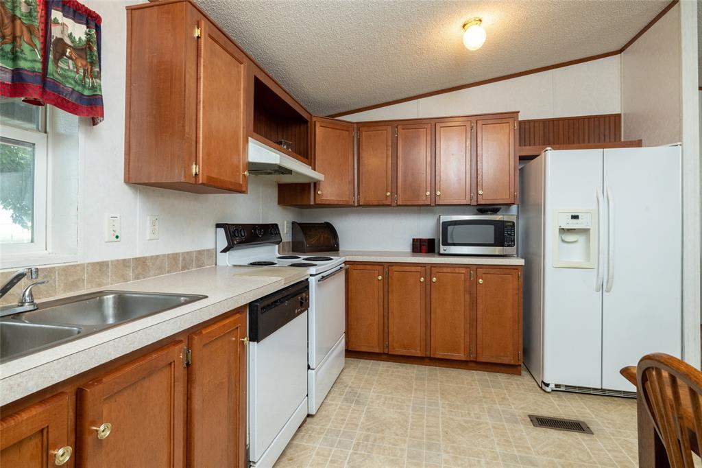 207 Lazy B Lane Springtown, TX 76082 - Photo 19 of 39 Kitchen featuring vaulted ceiling, light tile patterned floors, sink, a textured ceiling, and white appliances