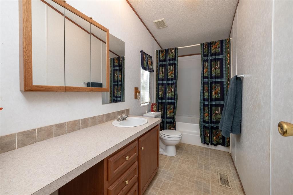 207 Lazy B Lane Springtown, TX 76082 - Photo 25 of 39 Full bathroom featuring vanity, shower / tub combo, tile patterned floors, a textured ceiling, and toilet