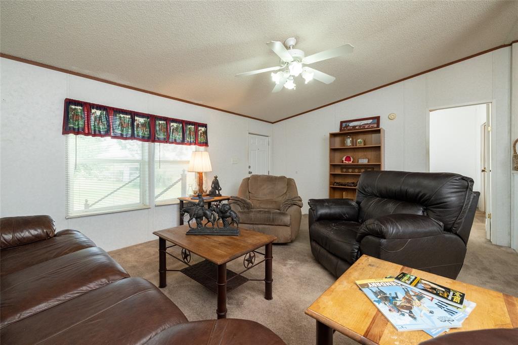 207 Lazy B Lane Springtown, TX 76082 - Photo 7 of 39 Carpeted living room featuring ceiling fan, vaulted ceiling, ornamental molding, and a textured ceiling