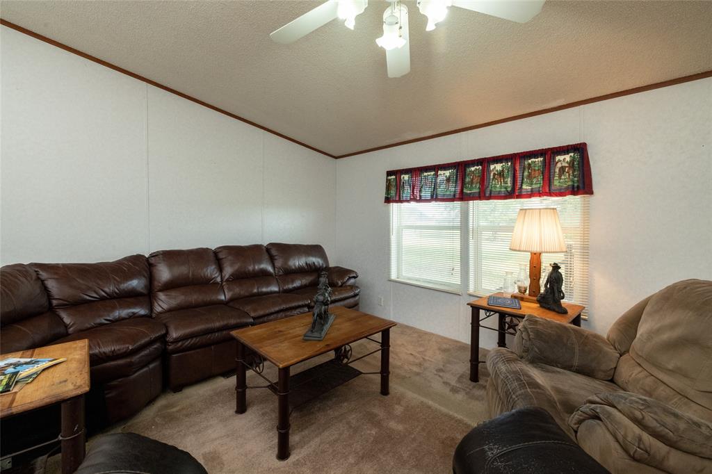 207 Lazy B Lane Springtown, TX 76082 - Photo 10 of 39 Carpeted living room with ceiling fan, a textured ceiling, and crown molding