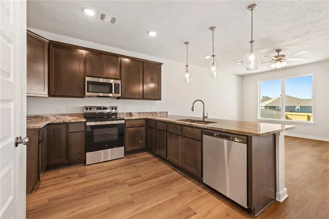 a kitchen with stainless steel appliances kitchen island granite countertop a sink stove and refrigerator