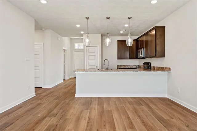 a living room with kitchen island granite countertop wooden floor and a view of living room