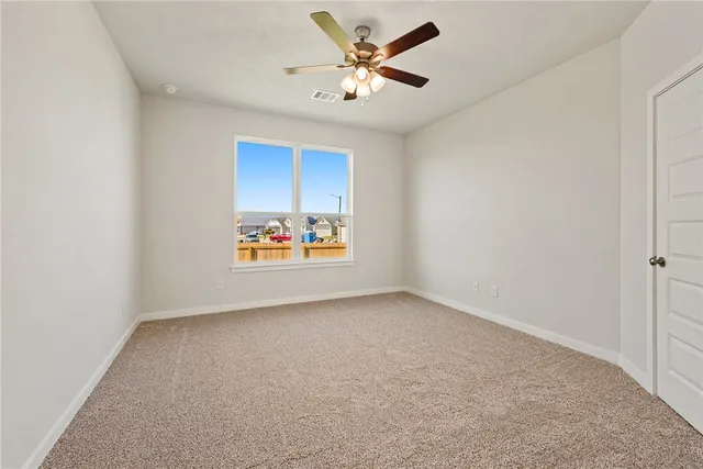 an empty room with a window and a ceiling fan