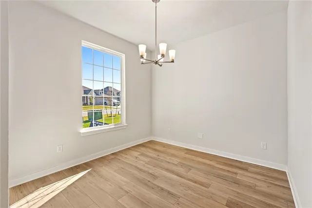an empty room with wooden floor chandelier fan and windows