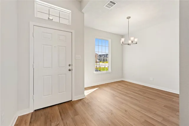 an empty room with wooden floor mirror and windows