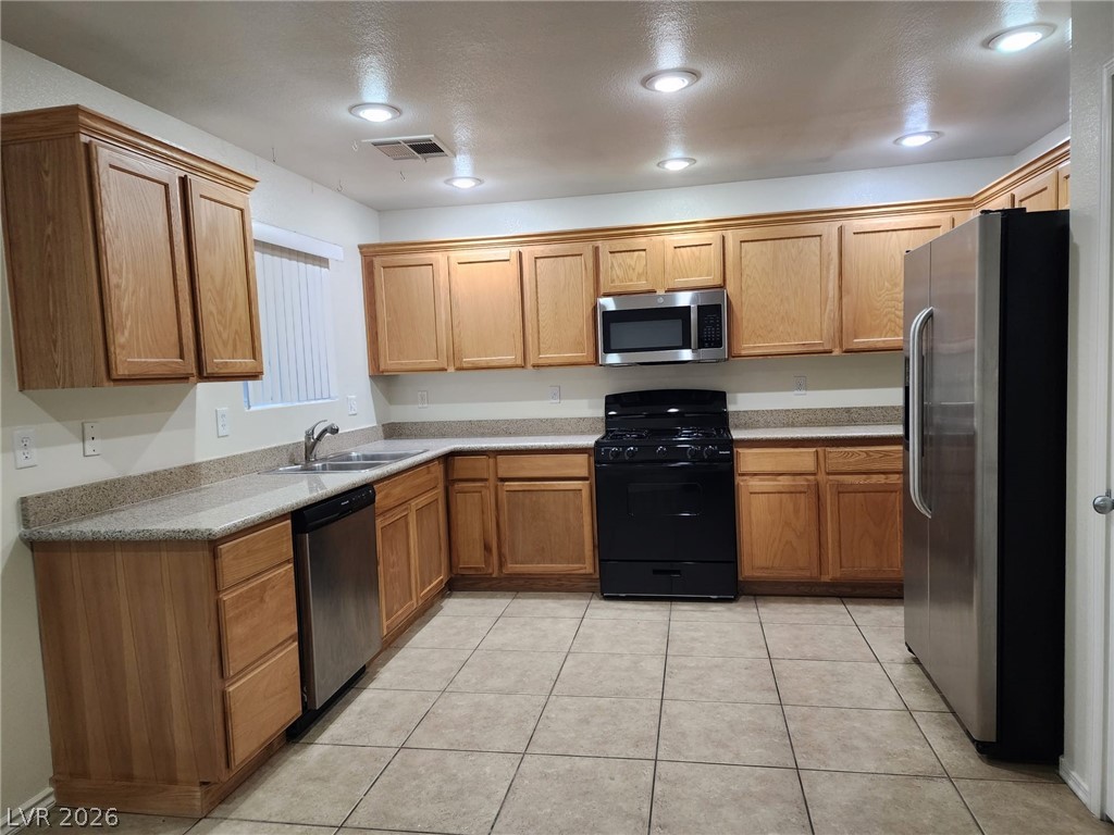 11901 Fairfax Ridge Street Las Vegas, NV 89183 - Photo 9 of 46 Kitchen with stainless steel appliances, light tile patterned flooring, brown cabinetry, light countertops, and recessed lighting