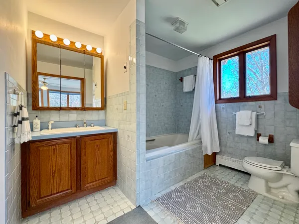 a bathroom with a bathtub sink mirror vanity and toilet