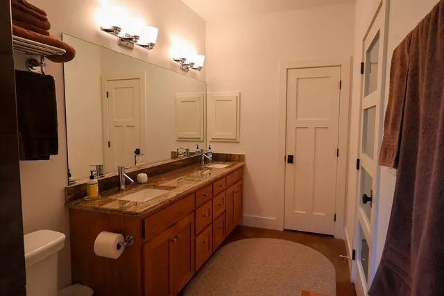 a bathroom with a granite countertop toilet sink and mirror