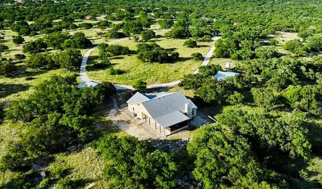 an aerial view of residential house with outdoor space and trees all around