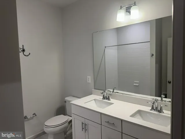 a bathroom with a toilet a sink a mirror and vanity