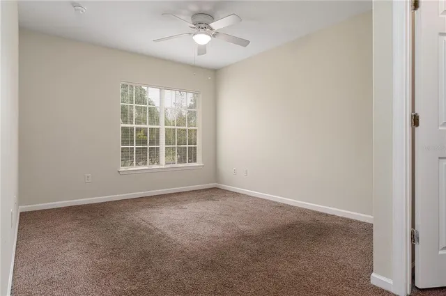 an empty room with windows and ceiling fan