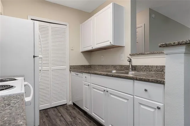 a kitchen with granite countertop white cabinets and white appliances