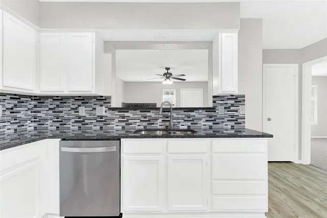 a kitchen with granite countertop white cabinets and sink