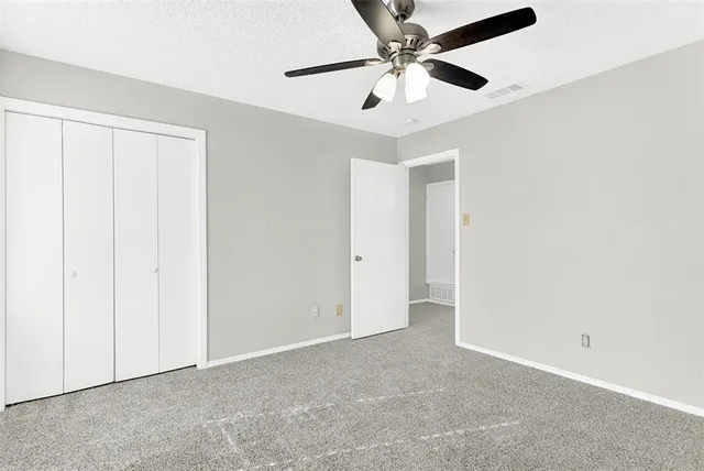 an empty room with a ceiling fan and a window