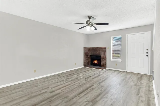 an empty room with wooden floor fireplace and fan