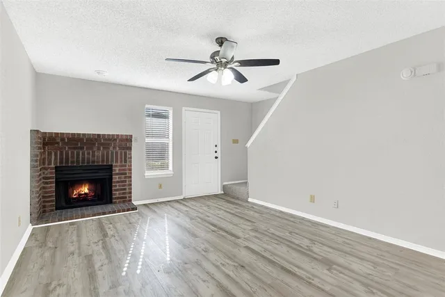 a view of empty room with wooden floor fireplace and fan