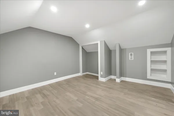 a view of an empty room with wooden floor and closet