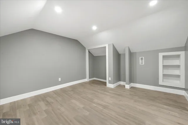 a view of an empty room with wooden floor and closet