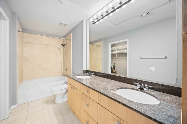 a bathroom with a granite countertop tub sink and mirror