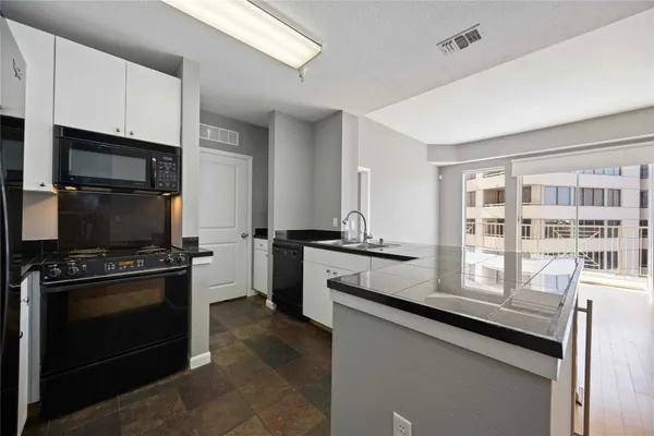 a kitchen with granite countertop a stove sink and microwave