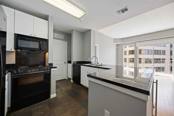 a kitchen with granite countertop a stove sink and microwave