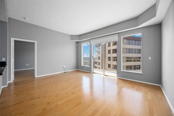 a view of an empty room with wooden floor and a window