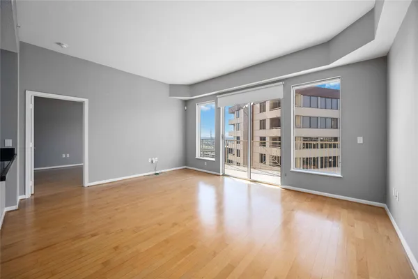 a view of an empty room with wooden floor and a window