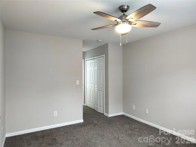 an empty room with closet and a chandelier fan